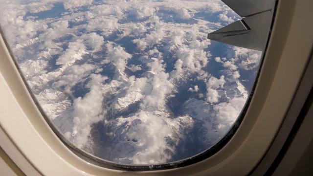从飞机窗口观看在雪云与冰川山体视频素材