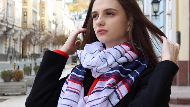 一名欧洲妇女在城市里用条纹围巾将长发拉直。视频下载