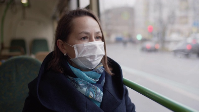 在公共汽车上戴着医用防护口罩的妇女视频下载
