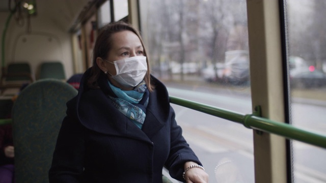 在公共汽车上戴着医用防护口罩的妇女视频下载