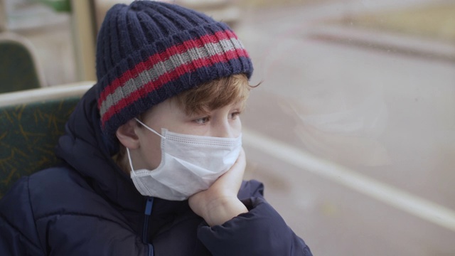 小男孩戴着医用防护口罩乘公共汽车旅行视频素材