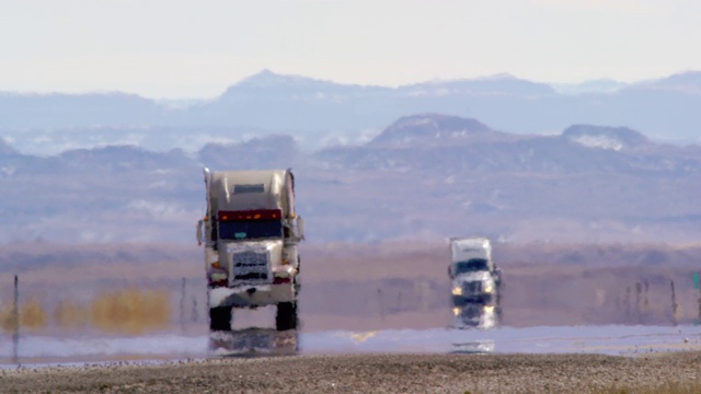 炎热的雾霾扭曲了半卡车在阳光明媚的一天沿着被群山环绕的犹他州州际公路行驶的视频视频下载