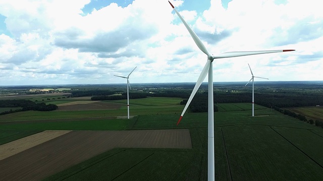3个带旋转转子的风力涡轮机在农田上发电，航拍照片视频素材