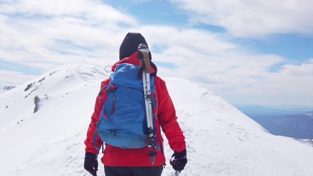 一名女性高山攀登者正在冬季与她的团队一起攀登高海拔的山峰视频下载