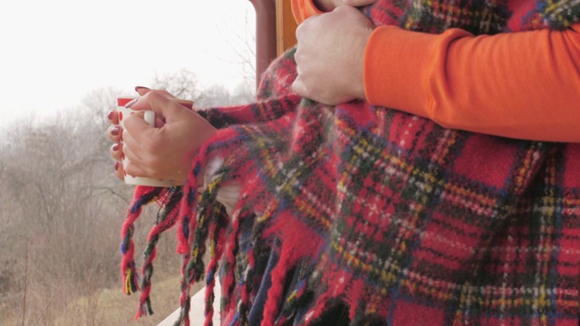 拥抱一对年轻的夫妇裹在毯子里，在室外的院子里享受寒冷的冬日视频下载