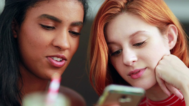 两个不同种族的女孩在看手机屏幕视频素材