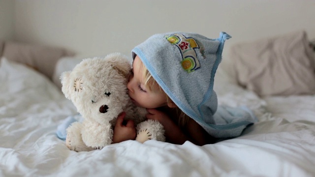 可爱的小男孩，沐浴后躺在床上放松，开心地笑着，白天视频素材