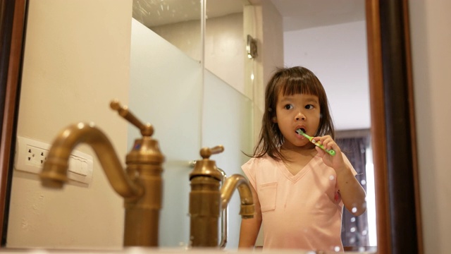 快乐的亚洲小女孩早上在浴室刷牙。口腔卫生的概念。视频下载