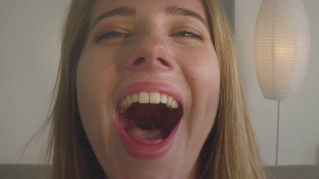 年轻漂亮的白人女性的特写镜头打开她的嘴，显示咽喉微笑愉快视频素材
