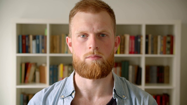 近距离拍摄的红发留胡子的白人男学生看着图书馆里的相机视频素材