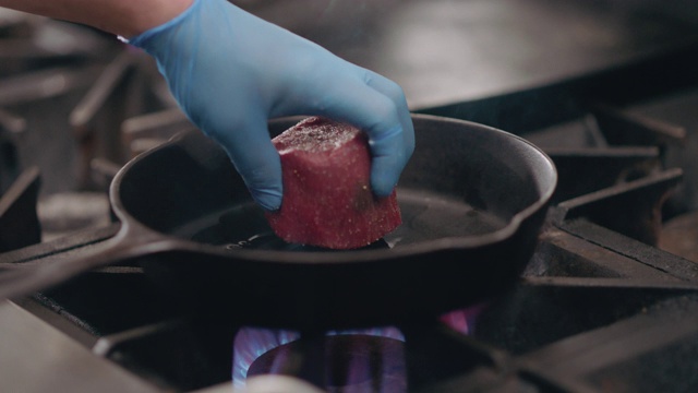 SLO MO:专业厨师在铸铁锅中加入生牛排视频素材