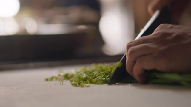 SLO MO专业厨师在砧板上切葱视频下载