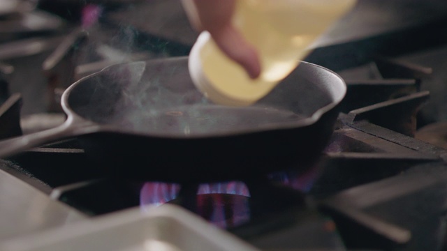 专业厨师在铸铁平底锅中加入食用油视频下载