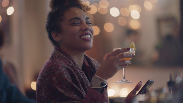 年轻的千禧一代女性独自坐在酒吧里用手机，对着镜头敬酒视频素材