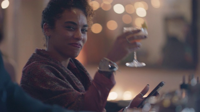 一个漂亮女人独自坐在酒吧里用手机，对着镜头敬酒视频素材