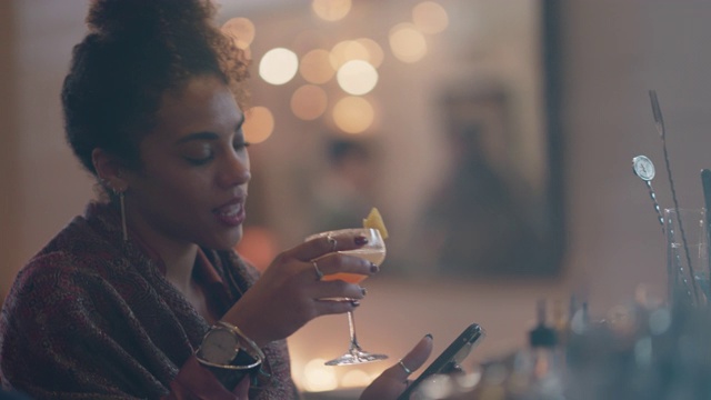 美丽的千禧女独自坐在酒吧喝酒，用她的手机，跳舞视频素材