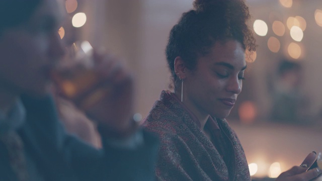 年轻的千禧一代女性独自坐在酒吧里用手机，看着镜头视频素材