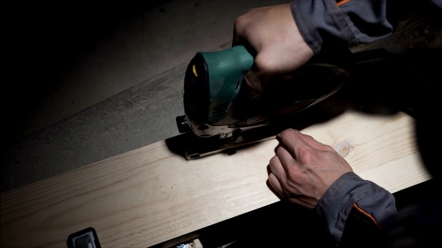 黑暗工人木工车间，工人使用拼图切割木材。低潮视频下载