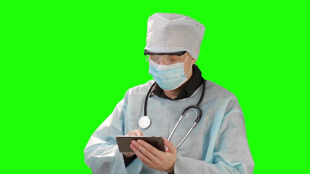 年轻医生在医用口罩和防护服中工作，在移动电话。在Chrome Key的背景上拍摄。铬凯高品质视频素材