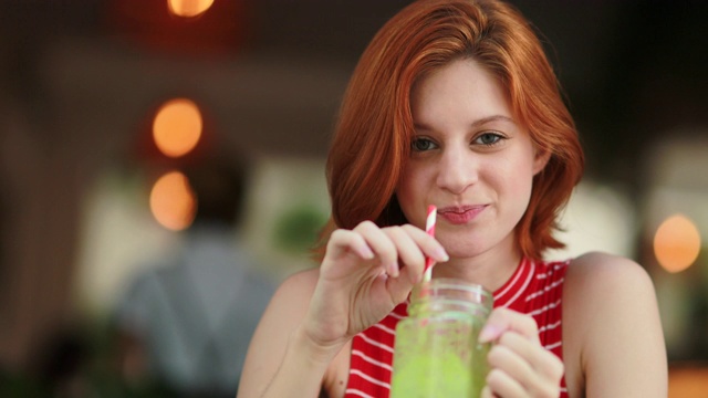 年轻女子喝排毒绿汁，红发美女捧健康天然饮品视频素材