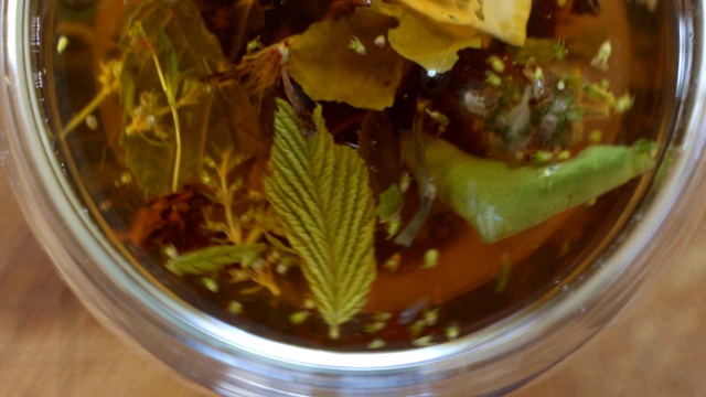 俯视图特写茶叶开放在热水在透明的杯子。用开水冲泡绿茶或红茶视频素材