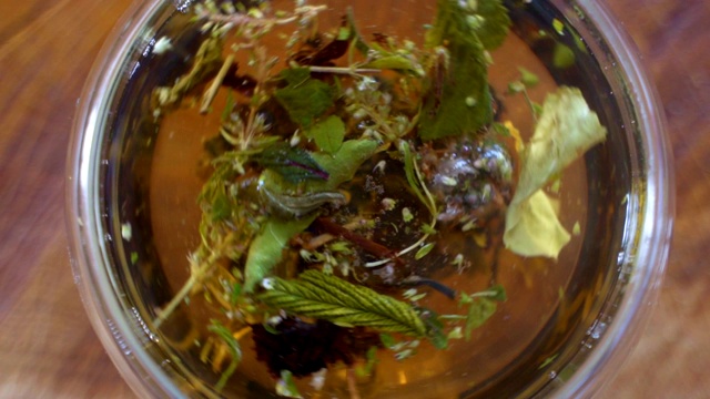 俯视图特写茶叶开放在热水在透明的杯子。用开水冲泡绿茶或红茶视频素材