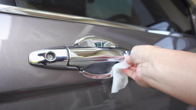 用手擦拭灰色汽车门把手表面，在家清洗covid-19病毒。视频素材
