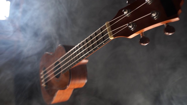 红木夏威夷尤克里里吉他孤立的黑色背景与烟雾视频下载