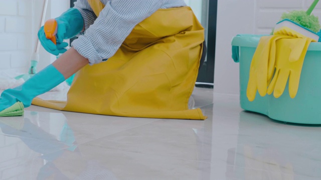 年轻的亚洲妇女打扫房间，她的地板清除污渍地板上的特殊清洁与喷雾的概念视频素材