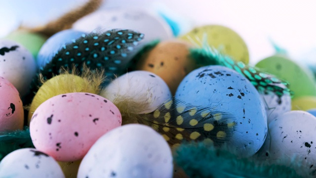 复活节彩蛋在一个巢与秋天彩色羽毛转向蓝色木制背景视频下载