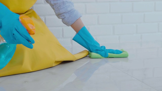 年轻的亚洲妇女打扫房间，她的地板清除污渍地板上的特殊清洁与喷雾的概念视频素材