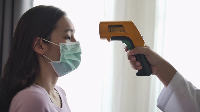 病人亚洲妇女的脸和医生的手用温度计检查温度视频下载