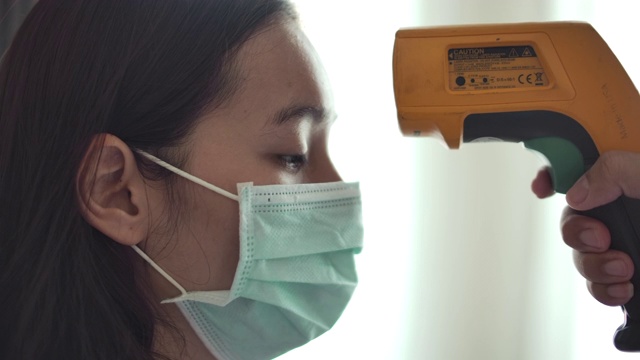 病人亚洲妇女的脸和医生的手用温度计检查温度视频下载