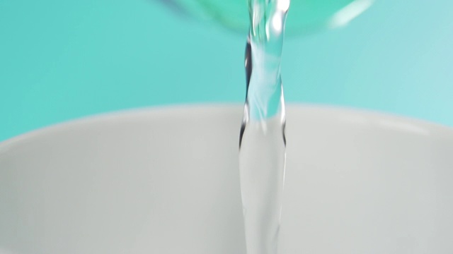 一股纯净的泉水充满了一个白色的杯子在蓝绿色的背景视频素材