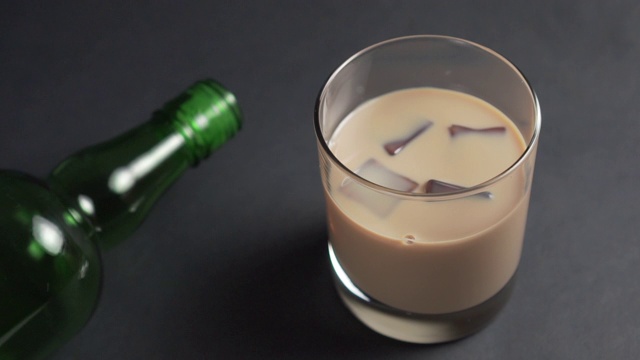 黑桌子上的一杯爱尔兰奶油烈酒里突然冒出冰块视频素材