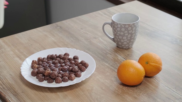 慢镜头将牛奶倒进装有巧克力玉米片的碗中，以240帧/秒的速度将牛奶滴到可可麦片早餐中，慢镜头是液体视频素材