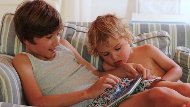 孩子在家里检查平板设备男孩在看屏幕视频素材