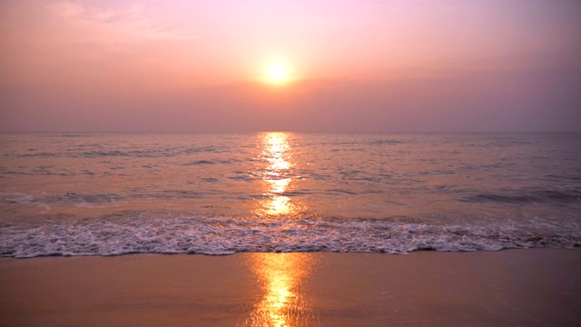 日落时海浪卷起白色沙滩的慢镜头视频素材