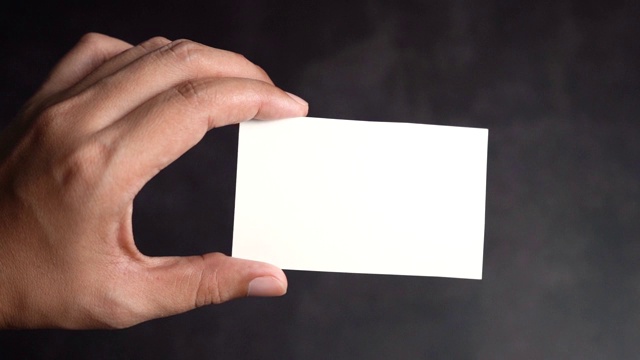 手握模型的白色名片在黑色的背景，缩小慢动作。视频素材