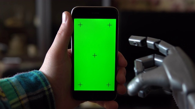 电子人使用电话。灰色的机械手向下滑动绿色屏幕的智能手机。色度键。4 k视频下载