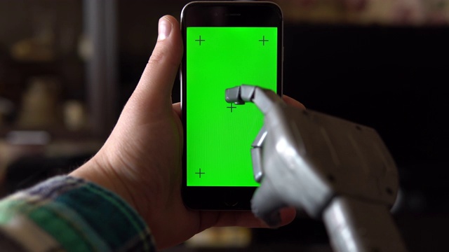 电子人使用电话。灰色的机械手正在绿色屏幕的智能手机上打字。色度键。4 k视频下载