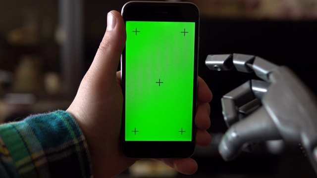 电子人使用电话。一只灰色的机械手正按在绿色屏幕的智能手机上。色度键。4 k视频下载