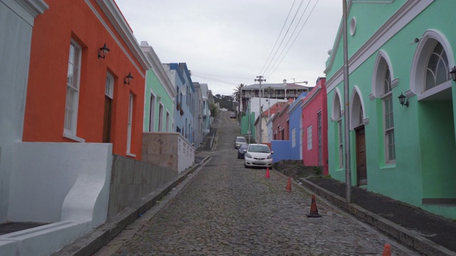 南非开普敦，一个引人注目的POV走在鹅卵石街道上，街道两旁排列着小汽车和色彩鲜艳的房子，风景如画视频下载
