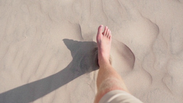 一名男子赤着脚在沙漠的沙子上行走，他正在秘鲁的偏远地区瓦卡奇纳度假视频下载