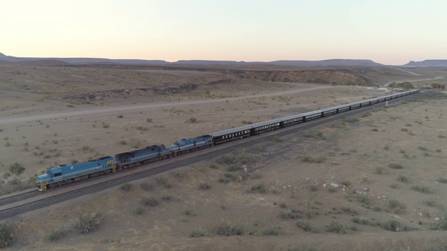 鸟瞰图的客运列车在风景在晴朗的天空日落，无人机向前移动沙漠-斯瓦科普蒙德，纳米比亚视频下载