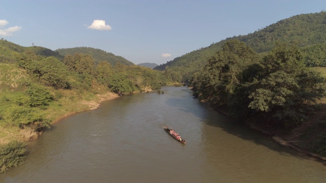 航拍在河上的船在树林中在阳光明媚的一天，无人机飞向山脉-湄公河，老挝视频素材