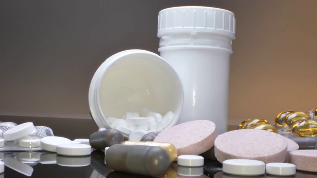 治疗理念，包装和罐子里的药物和药片散落在黑色的桌子上视频下载
