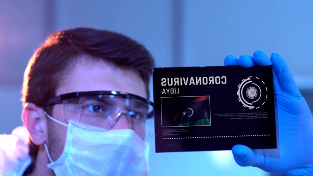 研究人员在实验室的数字屏幕上用利比亚国旗查看冠状病毒的结果视频下载