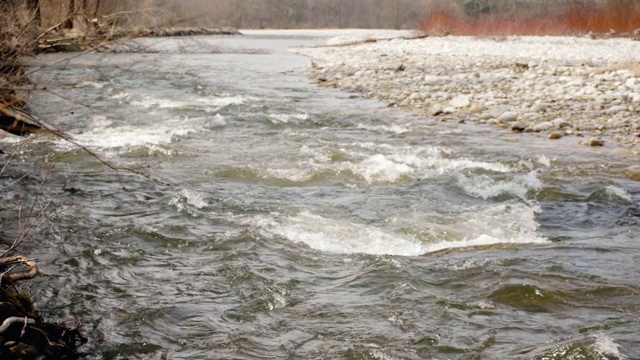春天河水流动，水形成白浪，圆石映岸，慢镜头录像视频素材