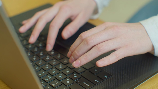 手打字在电脑键盘上，移动的相机，商务女性工作在笔记本电脑在办公室。视频素材